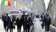 French President Emmanuel Macron (2ndL) and Senegalese President Macky Sall (2ndR), with their wives Brigitte Macron (L) and Marieme Faye Sall (R), cross the Faidherbe bridge in Saint-Louis, Senegal, February 3, 2018. REUTERS/Ludovic Marin/Pool
