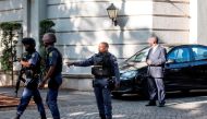 An armed South African Police member gestures as he leaves with colleagues the compound of the controversial business family Gupta while cars belonging to the Hawks, The Directorate for Priority Crime Investigation, are stationed outside, in Johannesburg,