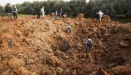 Palestinians check the site of an Israeli air strike in Gaza City on February 18, 2018. / AFP / MAHMUD HAMS 