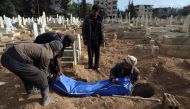 Syrians prepare to bury a body in Kafr Batna, in the besieged Eastern Ghouta region on the outskirts of the capital Damascus on February 22, 2018. AFP / Amer Almohibany