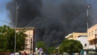 People watch as black smoke rises as the capital of Burkina Faso came under multiple attacks on March 2, 2018, targeting the French embassy, the French cultural centre and the country's military headquarters.  AFP / Ahmed Ouoba
