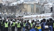 Activists stand as policemen destroy tents camp of supporters of Mikheil Saakashvili set in front of the Ukrainian parliament in Kiev, after they took it by force early morning on March 3, 2018.  / AFP / Sergei SUPINSKY