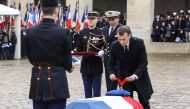 French President Emmanuel Macron (R) bows and places the posthumous medal of Commander in the Legion of Honor Order on the coffin of Lieutenant-Colonel Arnaud Beltrame, draped with the national flag, during a national ceremony on March 28, 2018 at the Hot
