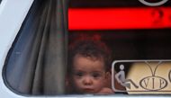 A child looks out of the window of a bus as they arrive in Qalaat al-Madiq, some 45 kilometres northwest of the central city of Hama, on April 2, 2018 after being evacuated from the Eastern Ghouta town of Douma. AFP / Omar Haj Kadour 