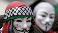 A Palestinian demonstrator wearing an Anonymous mask protests on the Israel-Gaza border, east of Gaza City in the central Gaza Strip, during the fifth straight Friday of mass demonstrations and clashes along the border with Israel on April 27, 2018.  AFP 