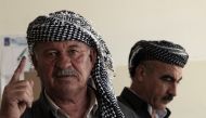 A member of the Kurdish Iraqi security shows his ink-stained index finger after voting at a polling station ahead of parliamentary elections in Arbil, the capital of the Kurdish autonomous region in northern Iraq on May 10, 2018. AFP / SAFIN HAMED