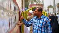 Iraqi voters read lists of candidates outside a polling station in the central holy city of Najaf on May 12, 2018 as the country votes in the first parliamentary election since declaring victory over the Islamic State (IS) group.   AFP / Haidar HAMDANI
