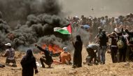 A Palestinian woman holding her national flag looks at clashes with Israeli forces near the border between the Gaza strip and Israel east of Gaza City on May 14, 2018, as Palestinians protest over the inauguration of the US embassy following its controver