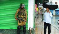 A Kashmiri muslim looks at an Indian paramilitary trooper standing guard amidst a heavy rainfall during a curfew in Srinagar, on July 27, 2016. AFP/ Tauseef Mustafa