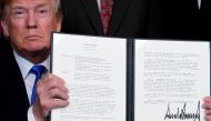 FILE PHOTO: US President Donald Trump holds a signed memorandum on intellectual property tariffs on high-tech goods from China, at the White House in Washington, US March 22, 2018. Reuters/Jonathan Ernst/File Photo