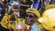 (FILES) In this file photo taken on November 8, 2017, shows Zimbabwe's President Robert Mugabe raising his fist as he greets party members and supporters gathered at his party headquarters to show support to Grace Mugabe becoming the party's next Vice Pre