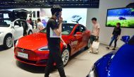 People look at cars in a Tesla showroom in Beijing on May 23, 2018. China announced on May 22 that it would cut tariffs on auto imports from July 1, the latest sign of a thaw in trade frictions with the United States. AFP / Greg Baker