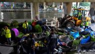 Municipal police officers of the city of Paris and workers clean up the Millenaire migrants makeshift camp along the Canal de Saint-Denis near Porte de la Villette, northern Paris, following its evacuation on May 30, 2018. / AFP / GERARD JULIEN 