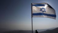 File photo of an Israeli soldier standing guard under an Israeli national flag during a tour made by Israeli parliament members in the Jordan Valley near the Jewish settlement of Maale Efrayim January 2, 2014. Credit: Reuters/Ronen Zvulun