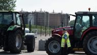 A French gendarme walks past tractors as French National federation of Agricultural Holders' Unions (FNSEA) and Young Farmers (Jeunes Agriculteurs, JA) union members block the access of a refinery in Reichstett, eastern France, on June 11, 2018 during a d