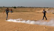 A Palestinian kicks a tear gas canister launched by Israeli soldiers as they intervened in a demonstration held within the 