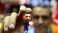 A sports shop keeper holds a figurine of Argentine football player Lionel Messi at a shop in Kuwait City on April 11, 2018. (AFP / Yasser Al-Zayyat) 