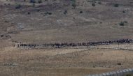 People start to walk away from the border fence between Israel and Syria at its Syrian side as it is seen from the Israeli-occupied Golan Heights near the Israeli Syrian border July 17, 2018. REUTERS/Ronen Zvulun