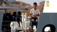 A migrant looks on from Italy's Diciotti coast guard vessel carrying 67 asylum seekers berthed at Trapani port on July 12, 2018.  AFP / Alessandro Fucarini


