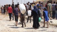Syrian citizens are seen with their belongings as they wait to leave Syria’s southwestern Daraa province with the 1st convoy on July 15, 2018.  (Ammar Al Ali/Anadolu Agency)

