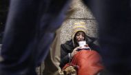 FILE PHOTO:  A homeless woman from north Wales, sits huddled under a sleeping bag next to her dog Casper in a shopping arcade near the Victoria rail station in central London December 14, 2012. Reuters/Chris Helgren