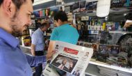A man takes a glance at a newspaper with a picture of US president Donald Trump on the front page, in the capital Tehran on July 31, 2018. Iran's currency traded at a fresh record-low of 119,000 to the dollar today, a loss of nearly two-thirds of its valu