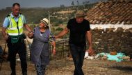 A Police officer evacuates locals due to a wildfire close to Monchique in the Portuguese Algarve, on August 4, 2018.  AFP / Carlos Costa
 