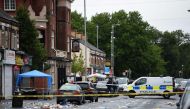Police officers stand guard at the scene of a shooting at Claremont Road in the Moss Side neighbourhood of Manchester, on August 12, 2018. (AFP / Oli SCARFF)