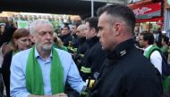 Jeremy Corbyn shakes hands with a fire-fighter lining the street as members of the public take part in a silent march on the first anniversary of the Grenfell fire on June 14, 2018. AFP / Daniel Leal-Olivas