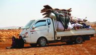 Displaced Syrians rest in the shade of a truck as they arrive with their belongings to a camp in Kafr Lusin near the border with Turkey in the northern part of Syria's rebel-held Idlib province on September 9, 2018.  AFP / Zein Al Rifai
