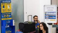 (FILES) In this file photo taken on August 10, 2018, Ryanair passengers sit on the terminal floor at Schoenefeld Airport in Berlin, after their Ryanair flight was cancelled because of a pilots strike. AFP / Odd ANDERSEN