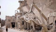 A Syrian child walks past the rubble of destroyed buildings in an opposition-held neighbourhood of the southern city of Daraa on October 2, 2018. / AFP / Mohamad ABAZEED