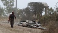 FILE PHOTO: A rebel fighter carries his weapon as he walks past the turret of a damaged tank at the Mastouma military base, after they seized it, in Idlib May 20, 2015. REUTERS/Ammar Abdullah