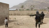 Cameroonian soldiers from the Rapid Intervention Brigade tell a young boy to stay back while on patrol in Kerawa, Cameroon, March 16, 2016. Joe Penney/Reuters