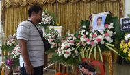 Boxing coach Somsak Deerujijaroen looks at a portrait of thirteen-year-old Muay Thai boxer Anucha Tasako during is funeral at a Buddhist temple in Samut Prakan province on November 14, 2018. AFP / Romeo GACAD