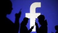 FILE PHOTO: Silhouettes of mobile users are seen next to a screen projection of Facebook logo in this picture illustration taken March 28, 2018. REUTERS/Dado Ruvic/Illustration