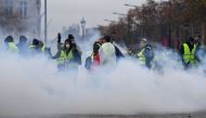 Demonstrators stand in the smoke of police grenades during a protest of Yellow Vests (Gilets jaunes) against rising oil prices and living costs on the Champs Elysees in Paris, on December 1, 2018. AFP / Alain Jocard 
