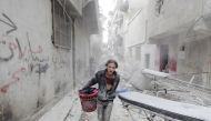 FILE PHOTO: A boy carries his belongings at a site hit by what activists said was a barrel bomb dropped by forces loyal to Syria's President Bashar al-Assad in Aleppo's al-Fardous district, Syria April 2, 2015. REUTERS/Rami Zayat