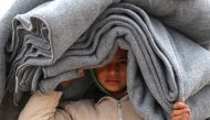 A Syrian displaced boy carries blankets over his head inside the Internallly Displaced Persons (IDP) camp of al-Hol in al-Hasakeh governorate in northeastern Syria on December 8, 2018.   AFP / Delil SOULEIMAN
