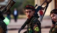 A Syrian Democratic Forces'(SDF) fighter holds a sniper rifle on his shoulder as he attends the funeral of a slain People's Protection Units (YPG) commander in the northeastern city of Qamishli on December 6, 2018. / AFP / Delil SOULEIMAN