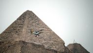 Belgian pilots fly their vintage Stampe OO-GWB biplane by one of the Pyramids of Giza on the southern outskirts of Cairo on November 13, 2016, during Vintage Air Rally (AFP) 