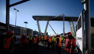 Workers and officials gather by remains of the Morandi Bridge for a preleminary meeting in Genoa on December 15, 2018.  AFP / Filippo MONTEFORTE