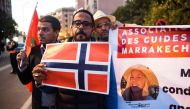 Moroccan tour guides hold up flags of Norway and Morocco as they gather to pay tribute to the two murdered Scandinavian hikers in the central city of Marrakesh on December 21, 2018.   AFP / FADEL SENNA