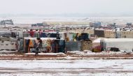 A Syrian refugee walks past makeshift shelters in an unofficial camp for refugees in Iaat in Lebanon's Bekaa valley, a snow storm on January 8, 2019.  / AFP