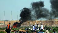 Palestinian medics raise up their hands as they try to evacuate a wounded demonstrator during protest at the Israel-Gaza border fence, in the southern Gaza Strip, yesterday.