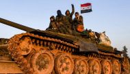 A Syrian soldier flashes the victory gestures as he sits with comrades atop a tank being transported near the northern town of Manbij, on January 12, 2019.  AFP / George OURFALIAN