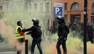 A protester speaks with French riot officers amid smoke during an anti-government demonstration called by the Yellow Vests 
