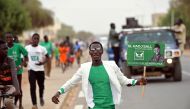 A supporter runs holding an election poster of the Party of Unity and Assembly (PUR) candidate Issa Sall during his campaign in Dahra Djoloff, Louga region, Senegal February 18, 2019.  Reuters/Sylvain Cherkaoui

 