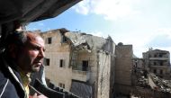 Syrian Izzat al-Dahan, 50, stands at the balcony of his family flat situated in a building heavily damaged during battles between rebel fighters and regime forces, in the former opposition held district of Salaheddin in the northern Syrian city of Aleppo 