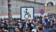 Algerian demonstrators hold a placard with the symbol of a man on a wheelchair, during a demonstration against Algeria's president's candidacy for a fifth term, on February 22, 2019 in Algiers. AFP / Ryad Kramdi 